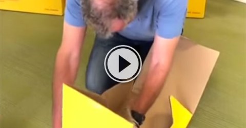 A man in blue tee searches through a yellow box!