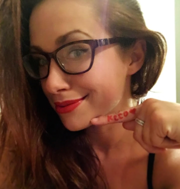 Geek girl with lined eyes showing her first finger with KCCO written on it with red lipliner