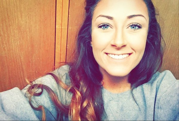 Brunette with blue eyes smiles for a selfie in grey tee