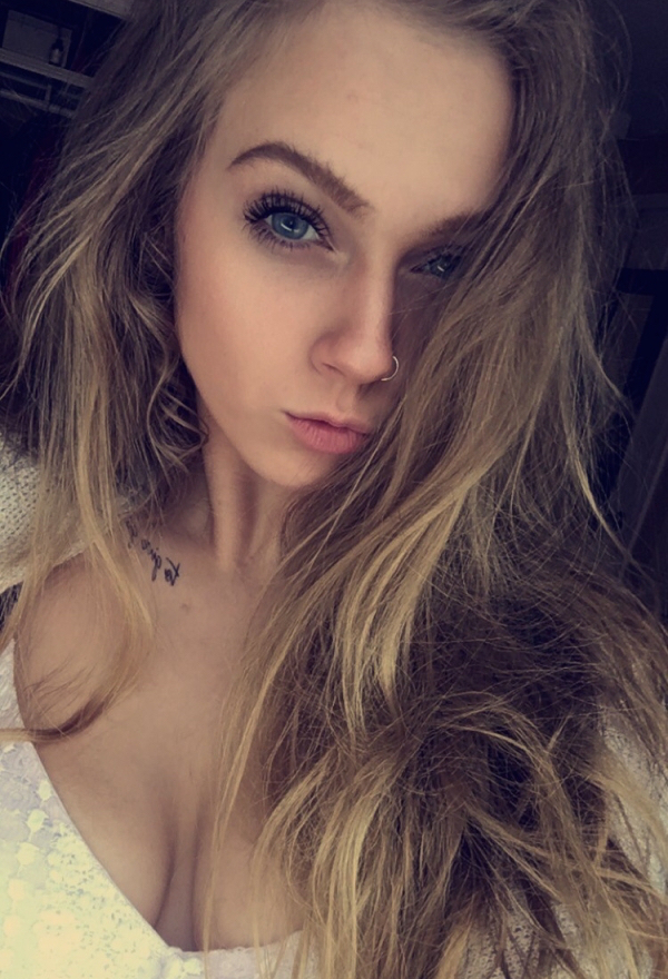 Blonde with light eyes and nose ring takes selfie of perky boobs and cleavage in white top