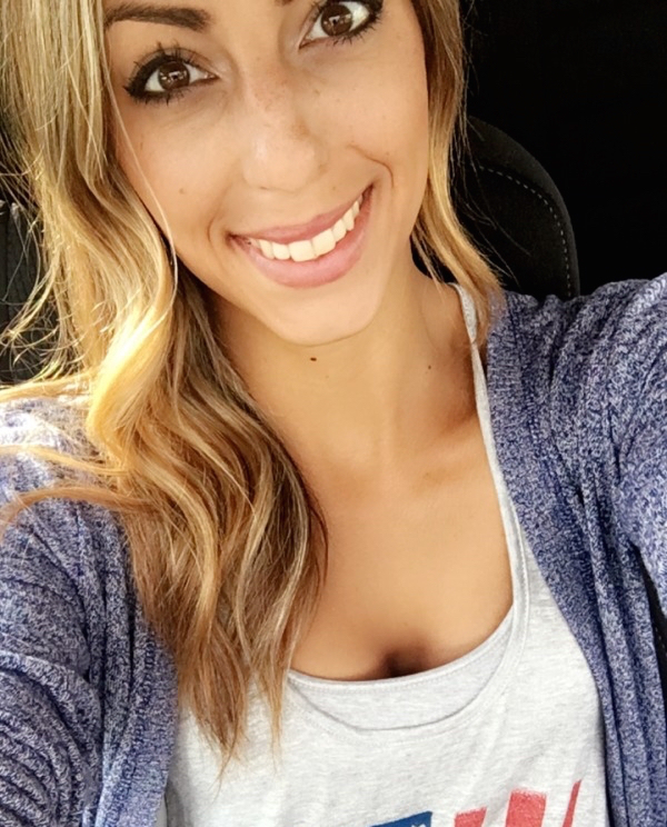 Girl with brown eyes clicks a car selfie wearing a white top beneath a blue sweater