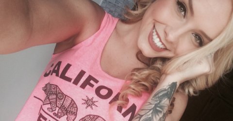 Blonde with light eyes smiles for selfie in pink top
