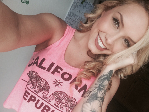 Blonde with light eyes smiles for selfie in pink top