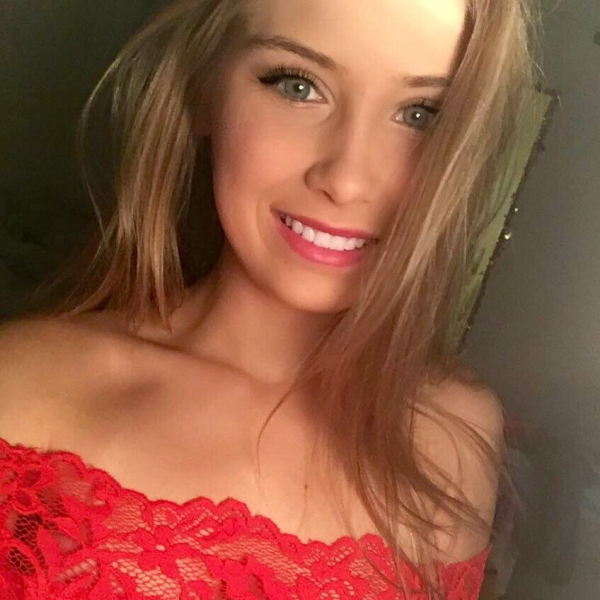 Cute babe with green eyes wearing a red dress smiles