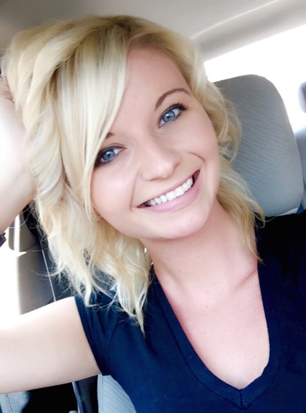Short haired blonde girl smiling for the camera in a car having bright blue eyes