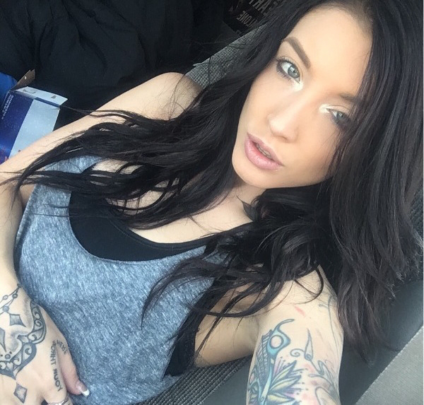 Tattooed brunette with light eyes takes selfie black bra and grey top