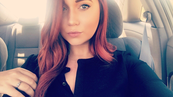 Blue eyed girl with red hair clicks a selfie in her car