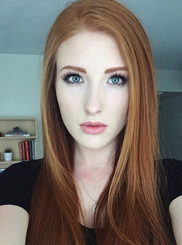 Beautiful red haired girl with blue eyes clicks a selfie