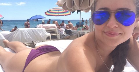 Topless girl in blue RayBan Aviators relaxing on her boobs wearing purple panties smiles for the photo